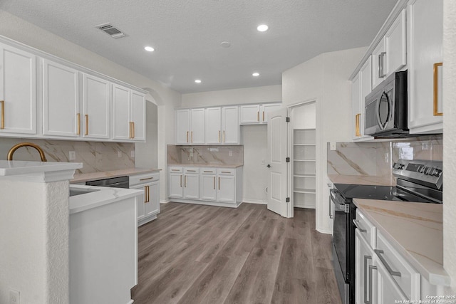 kitchen with visible vents, appliances with stainless steel finishes, white cabinetry, and light wood-type flooring