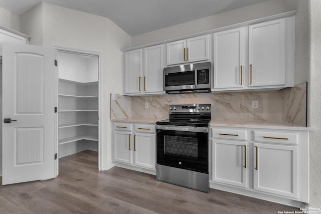 kitchen with tasteful backsplash, white cabinets, and stainless steel appliances