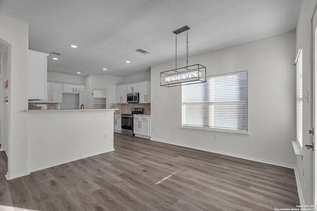 kitchen with white cabinets, wood finished floors, visible vents, and appliances with stainless steel finishes