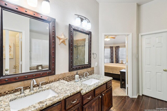 ensuite bathroom featuring double vanity, connected bathroom, wood finish floors, and a sink