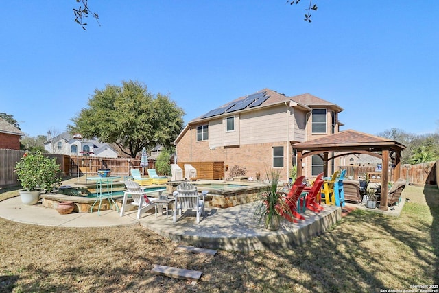 back of house featuring a gazebo, a fenced backyard, a yard, a patio area, and an outdoor hot tub