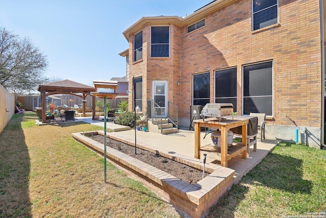 rear view of property featuring a gazebo, a patio area, brick siding, and a lawn