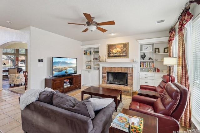 living room with light tile patterned floors, visible vents, arched walkways, and plenty of natural light