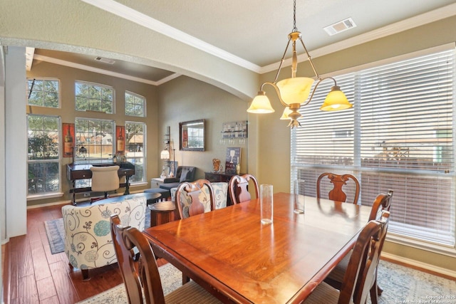 dining area featuring hardwood / wood-style floors, arched walkways, visible vents, and ornamental molding