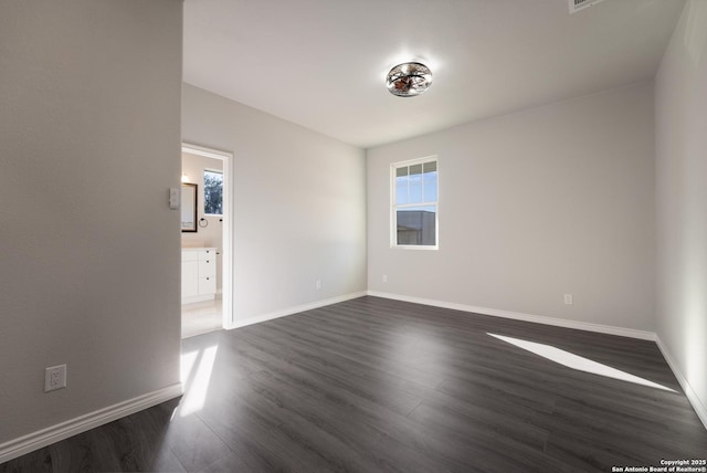 spare room with baseboards and dark wood-style flooring