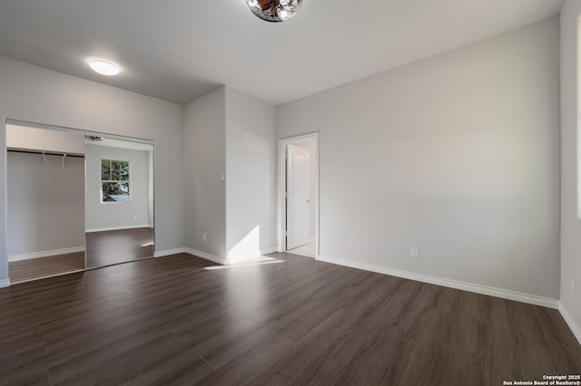 spare room featuring dark wood finished floors and baseboards