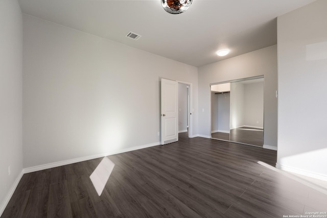 unfurnished bedroom with a closet, baseboards, visible vents, and dark wood-style flooring