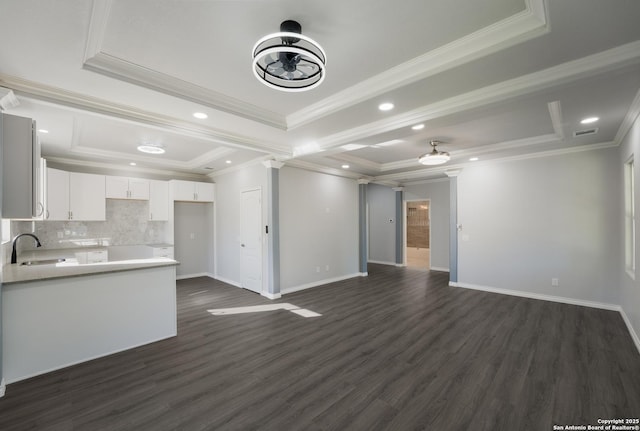 unfurnished living room featuring a raised ceiling, baseboards, and dark wood-style flooring