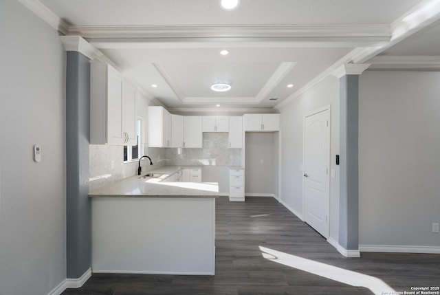 kitchen featuring ornamental molding, white cabinetry, a raised ceiling, and a sink