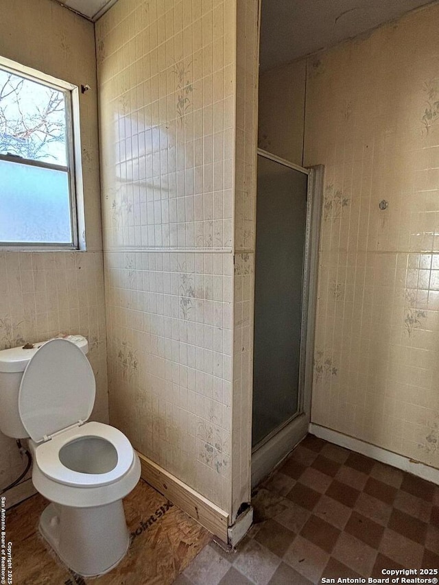 full bathroom with tile walls, toilet, a stall shower, and tile patterned floors