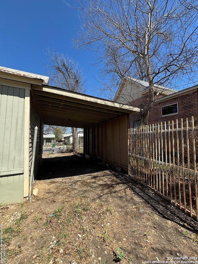 view of vehicle parking featuring a carport and fence