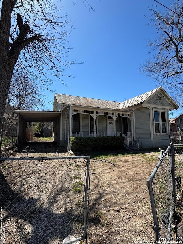 view of front of house with a fenced front yard, a carport, and covered porch