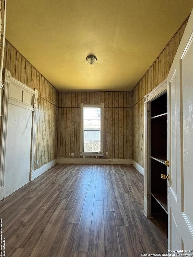 spare room with baseboards and dark wood-style flooring