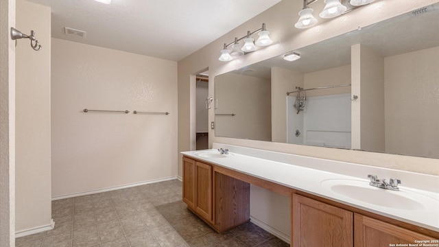 bathroom featuring double vanity, walk in shower, visible vents, and a sink