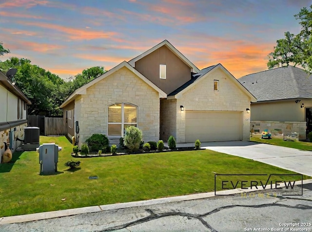 view of front of house with concrete driveway, central air condition unit, a garage, and a front yard