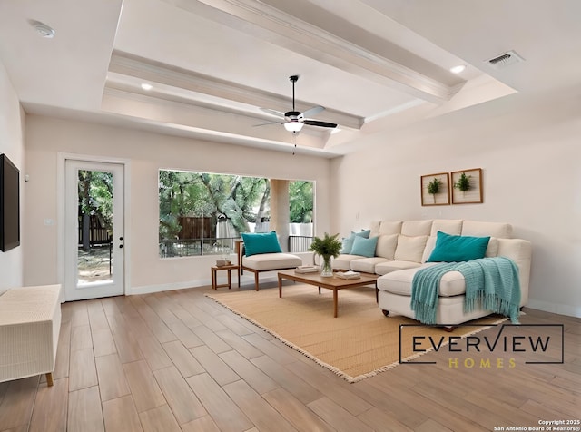 living room featuring a tray ceiling, wood finished floors, and baseboards