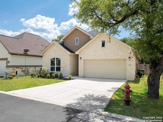 view of front facade featuring driveway, an attached garage, and a front lawn