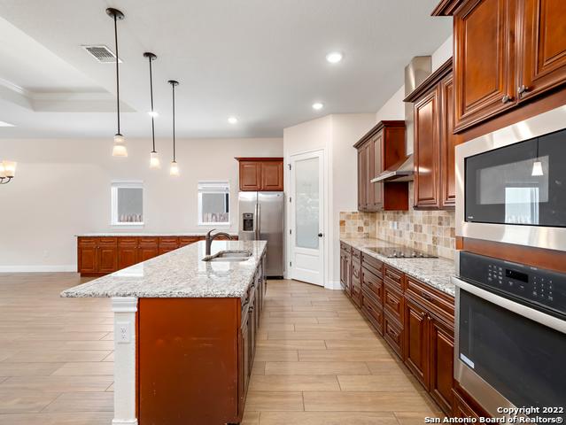 kitchen with visible vents, a center island with sink, a sink, appliances with stainless steel finishes, and decorative backsplash