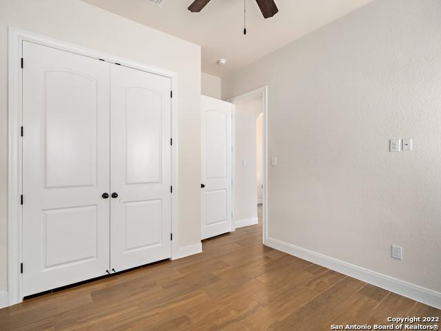 unfurnished bedroom with a closet, baseboards, wood finished floors, and a ceiling fan