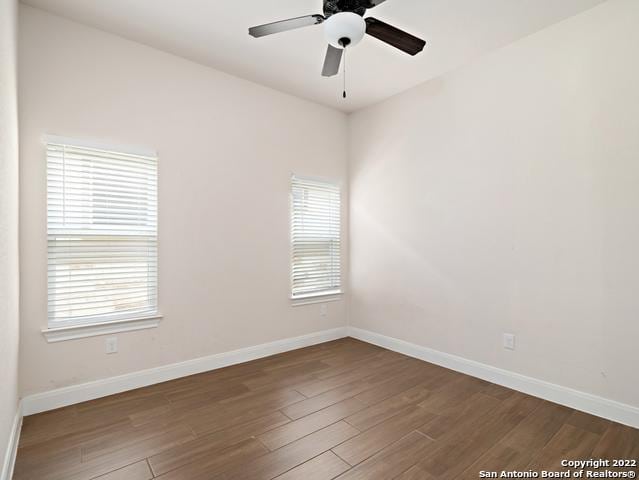 unfurnished room with baseboards, a healthy amount of sunlight, and wood finished floors