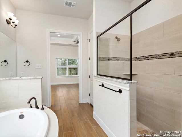 full bath with visible vents, a garden tub, wood finished floors, baseboards, and walk in shower