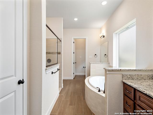 full bath featuring baseboards, a garden tub, recessed lighting, tiled shower, and vanity