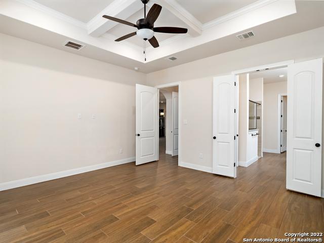 unfurnished bedroom featuring dark wood finished floors, visible vents, baseboards, and ornamental molding