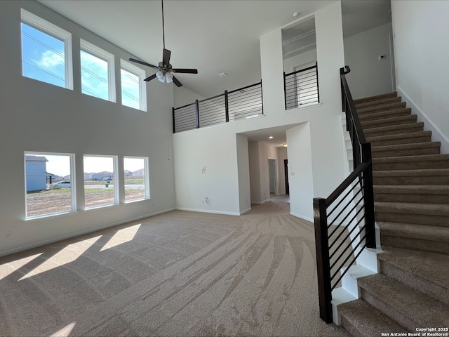 unfurnished living room with baseboards, plenty of natural light, carpet, and a ceiling fan