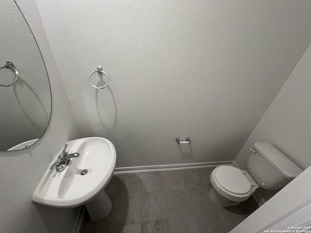 bathroom with a sink, baseboards, and toilet