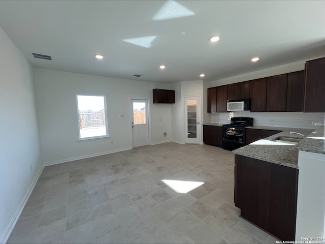 kitchen with visible vents, a sink, light stone counters, black gas stove, and dark brown cabinets