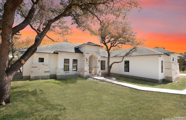 view of front of home with stucco siding and a lawn