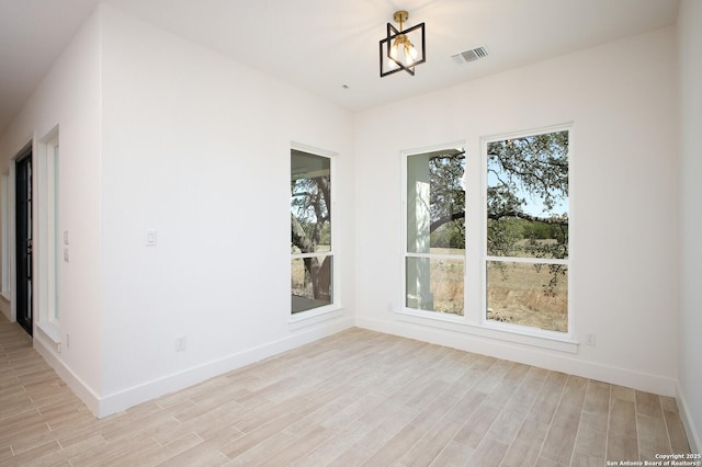 spare room featuring visible vents, baseboards, and light wood finished floors