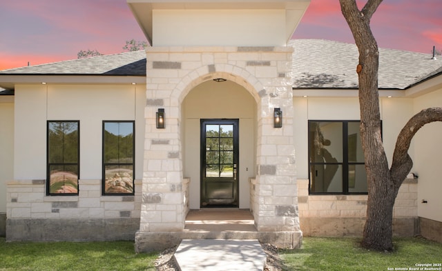 entrance to property featuring crawl space, stone siding, and a shingled roof