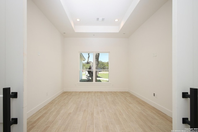 spare room with visible vents, light wood-style flooring, recessed lighting, baseboards, and a raised ceiling