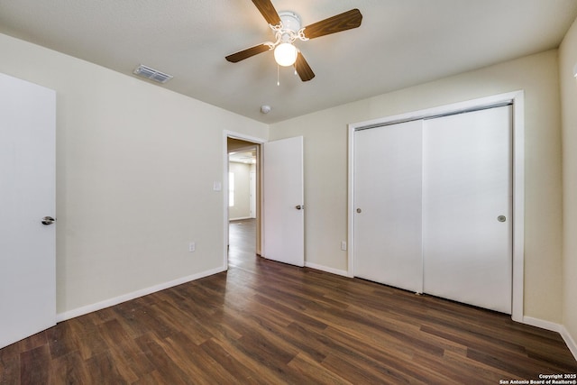 unfurnished bedroom featuring visible vents, baseboards, a closet, and dark wood-style floors