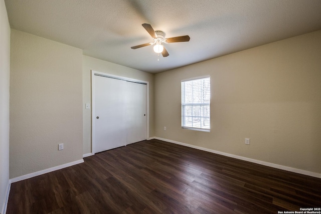 unfurnished bedroom with baseboards, dark wood-style flooring, ceiling fan, a closet, and a textured ceiling