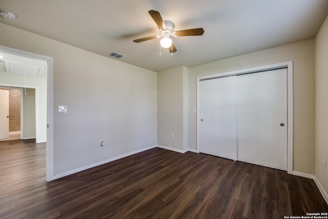 unfurnished bedroom with visible vents, dark wood-style floors, a closet, baseboards, and attic access