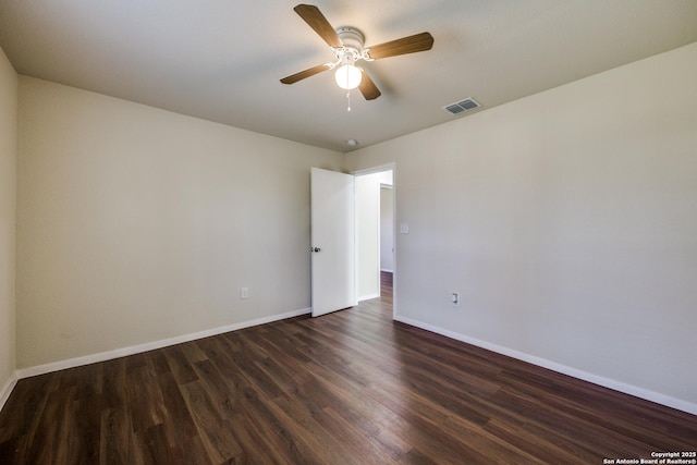 unfurnished room with dark wood finished floors, baseboards, visible vents, and a ceiling fan