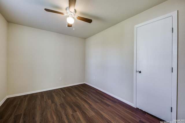 unfurnished room featuring dark wood-style floors, a ceiling fan, and baseboards