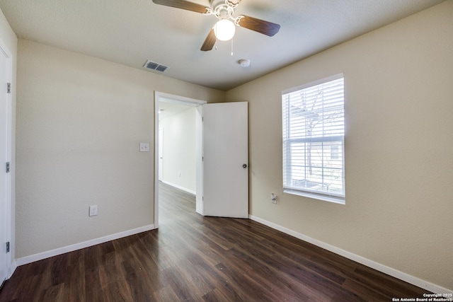 empty room featuring dark wood-type flooring, baseboards, visible vents, and ceiling fan