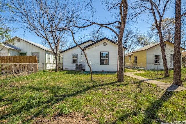 rear view of house featuring a yard and fence