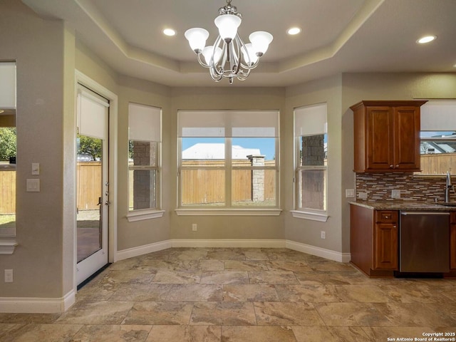 kitchen featuring a raised ceiling, backsplash, baseboards, dishwasher, and a chandelier