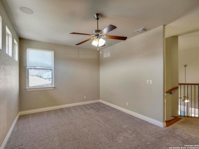 carpeted spare room with visible vents, baseboards, and ceiling fan