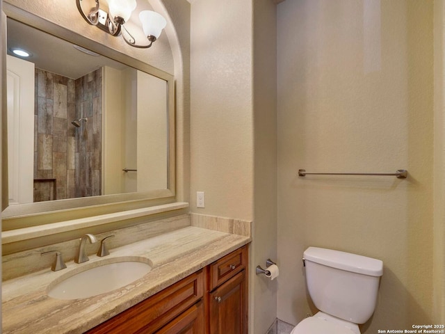 bathroom featuring vanity, toilet, and a tile shower