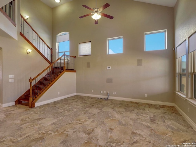 unfurnished living room with a wealth of natural light, a high ceiling, and baseboards