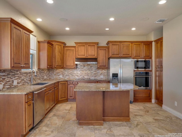 kitchen with visible vents, a center island, under cabinet range hood, stainless steel appliances, and a sink