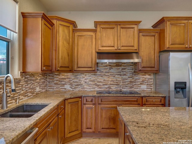 kitchen featuring extractor fan, light stone counters, decorative backsplash, appliances with stainless steel finishes, and a sink