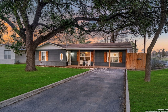 view of front of house with brick siding, covered porch, driveway, and a yard