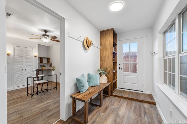 entryway with visible vents, ceiling fan, baseboards, and wood finished floors