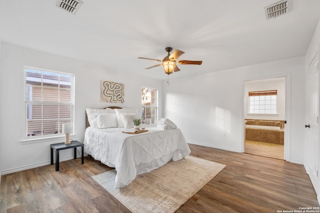 bedroom featuring connected bathroom, visible vents, and wood finished floors